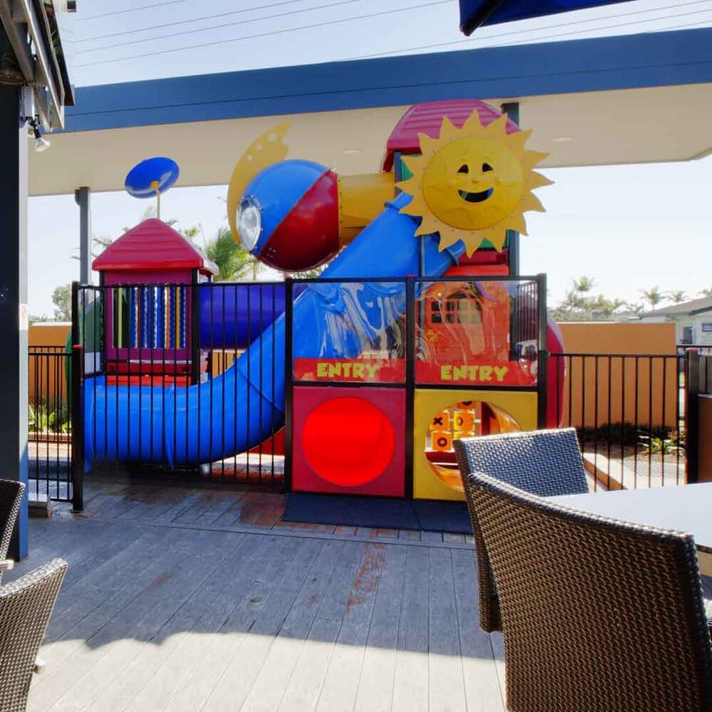 Colourful enclosed playground with slides and climbing tunnels at Westower Tavern in Ballina, next to outdoor dining tables.
