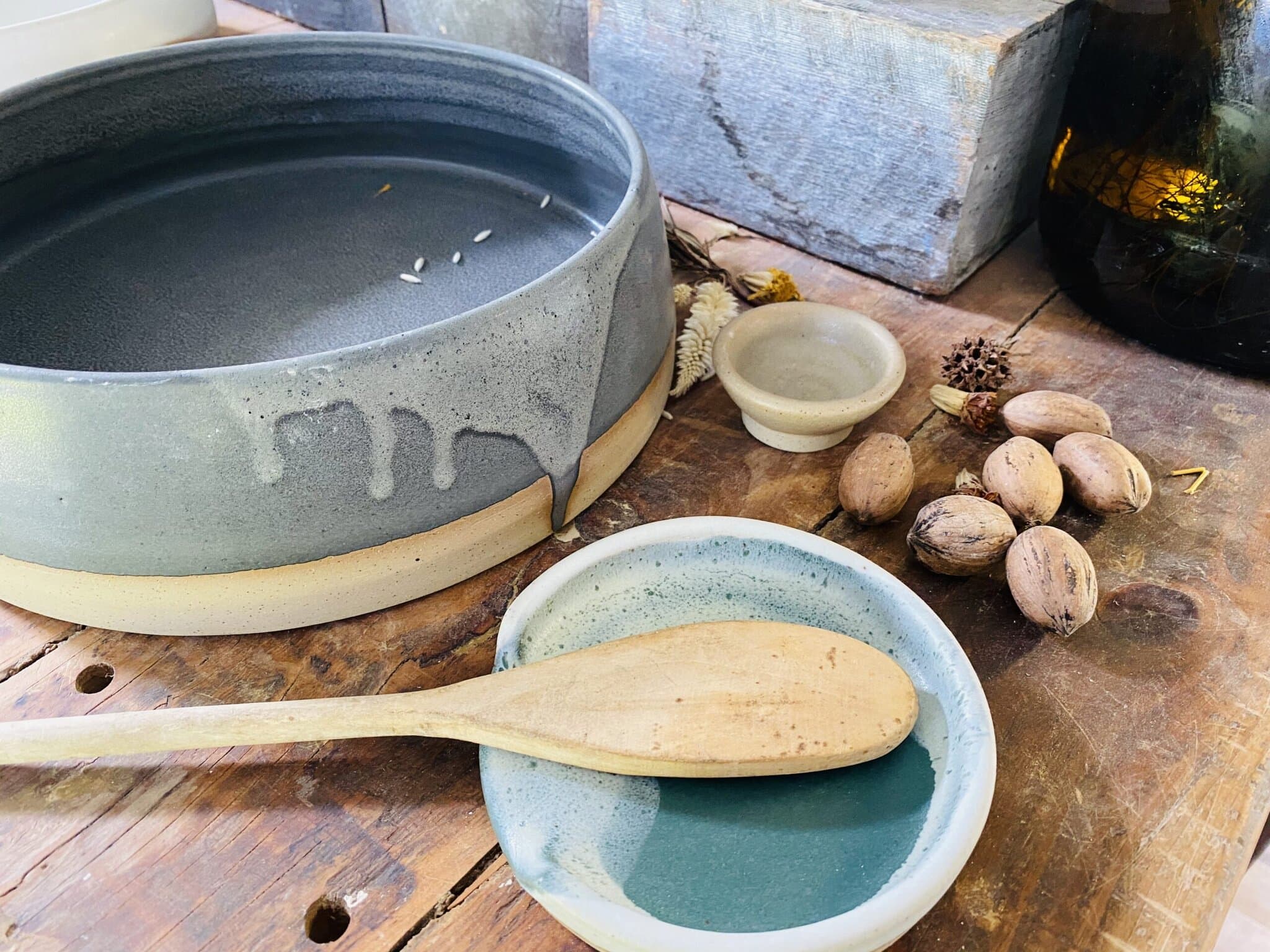 Handcrafted ceramic mug with green and white glaze made by Brooke Clunie in the Northern Rivers, held over a timber saucer.