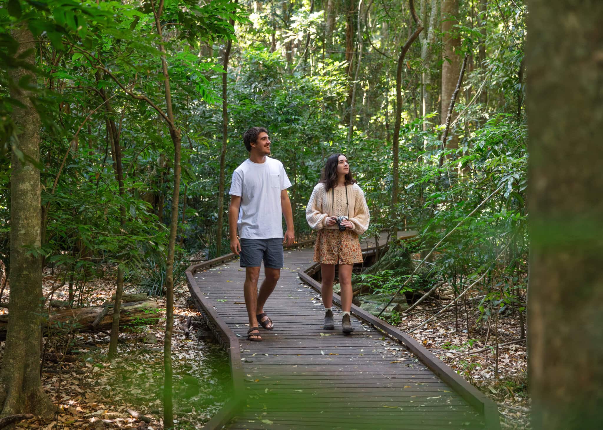 Young couple exploring the lush rainforest boardwalk trail at Victoria Park Nature Reserve in Alstonville, Ballina hinterland.