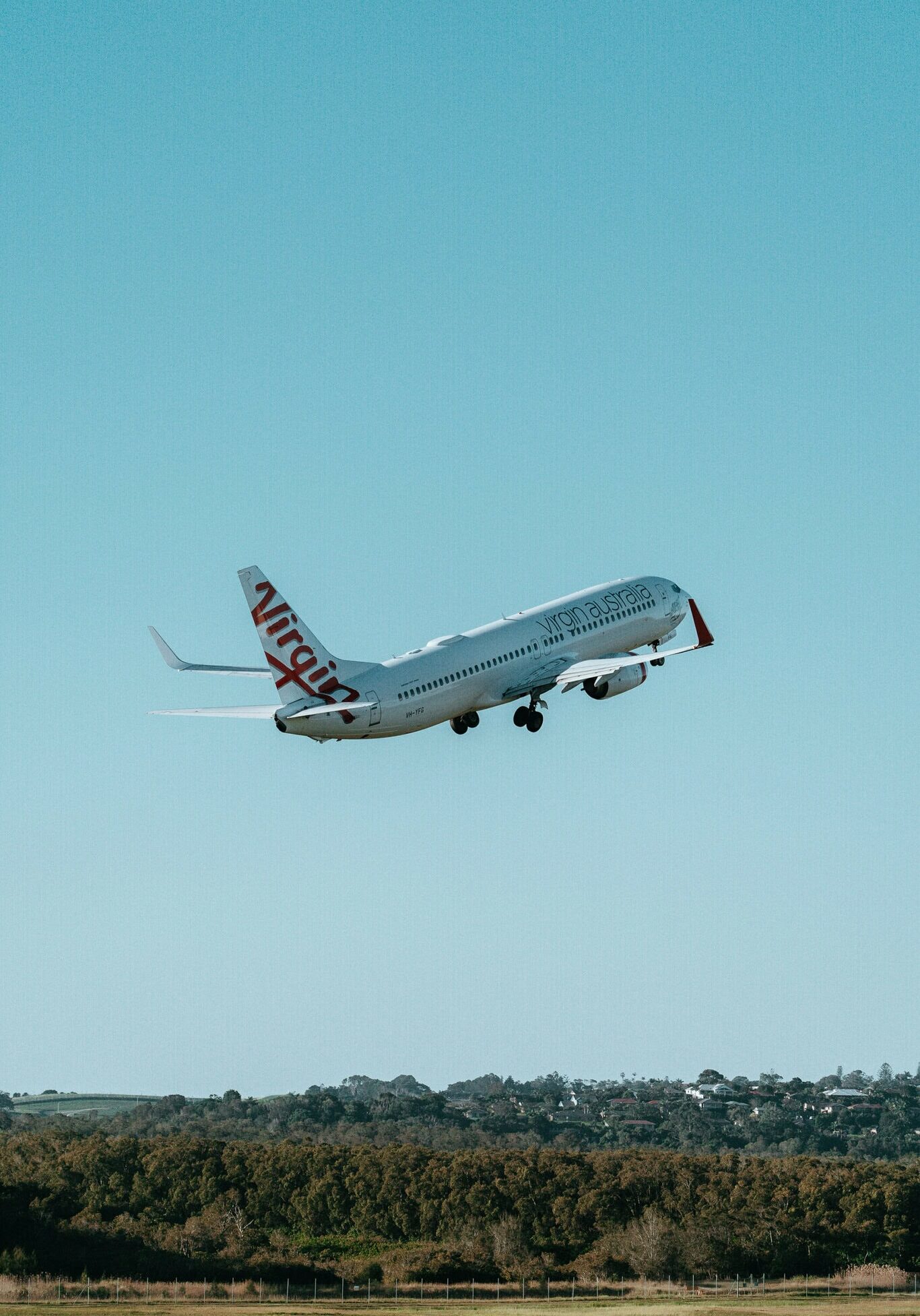 Aircraft taking off from Ballina Byron Gateway Airport with clear blue skies above.