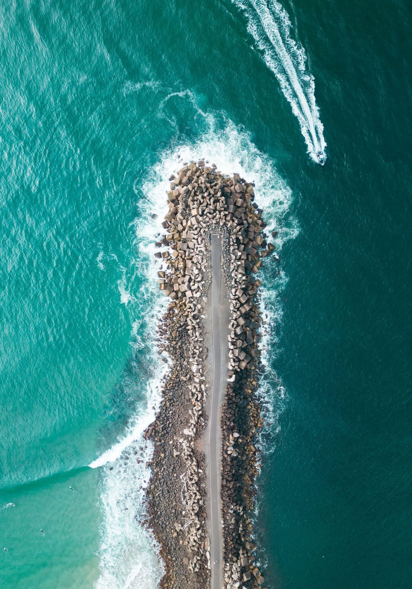 Aerial view of North Wall Ballina stretching into the ocean with waves and a speedboat nearby.