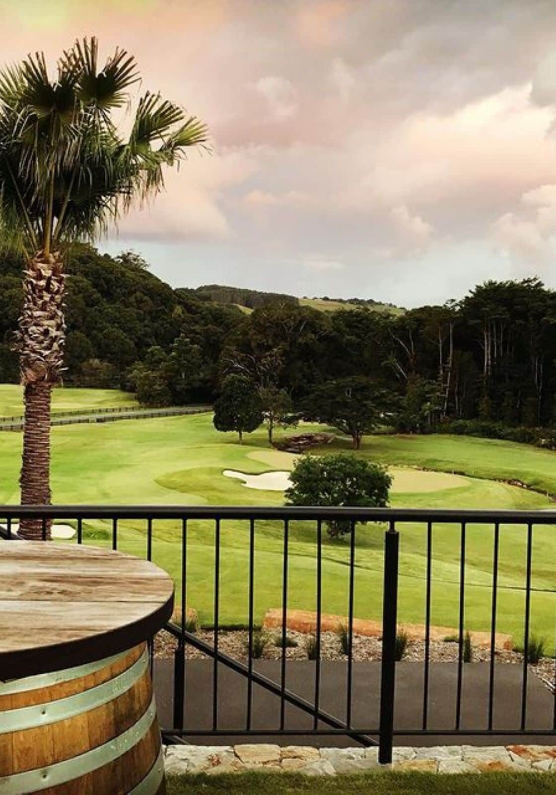 Scenic view over Teven Valley Golf Course in Northern NSW, with lush fairways, palm trees, and a forested hinterland backdrop